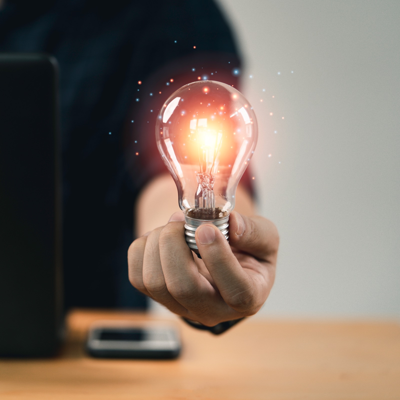 Hand holding a glowing lightbulb